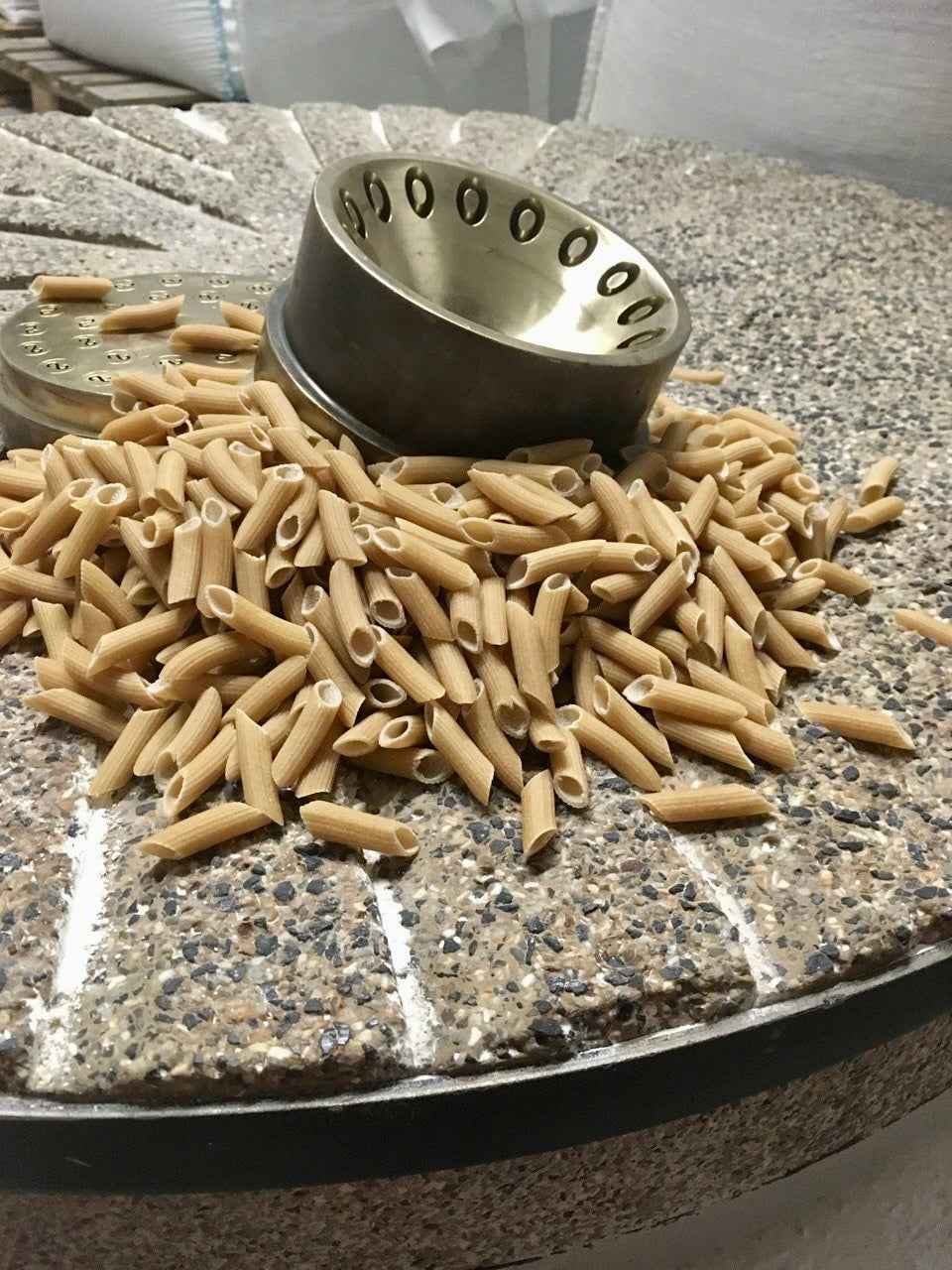 Spent grain pasta on stone press alongside bronze die.